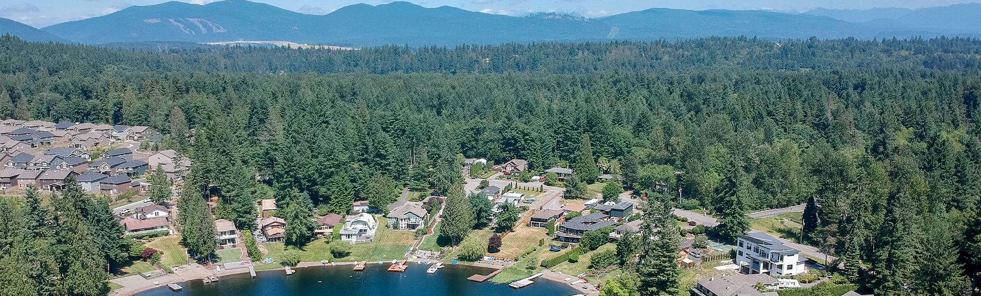 Tranquil Shady Lake on a bright clear day in summertime with trees reflecting in the water a blue sky and white clouds with lily pads dockside in Renton King County Washington State