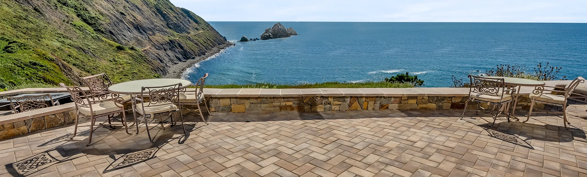 Incredible ocean view beyond a paver patio.