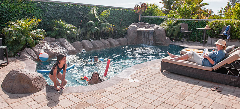 Pool deck with pavers and family enjoying the pool