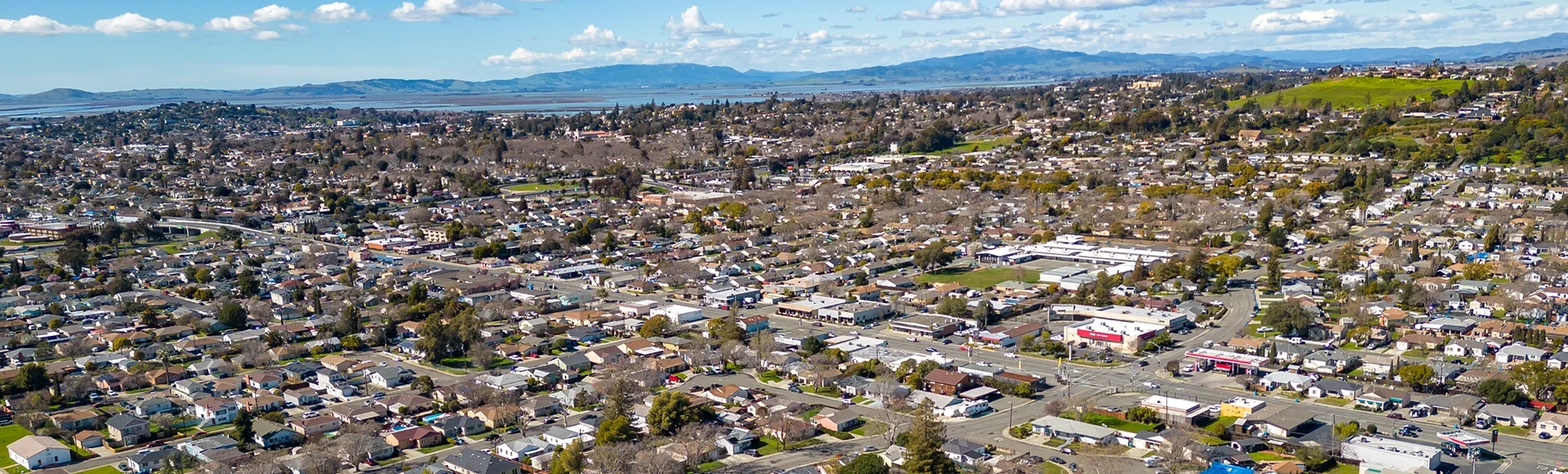 Aerial photos over a community in Vallejo, California with houses, streets, cars and parks on a sunny day in March.