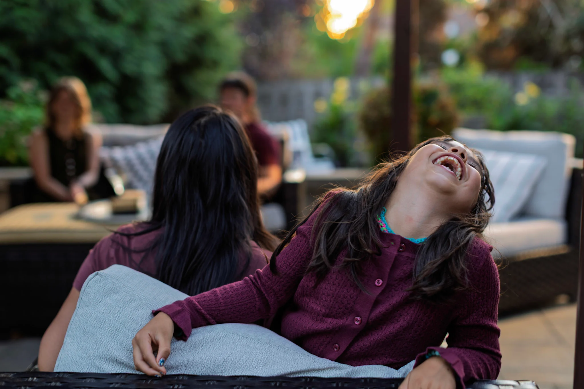 Laughing little girl with family and friends under pergola