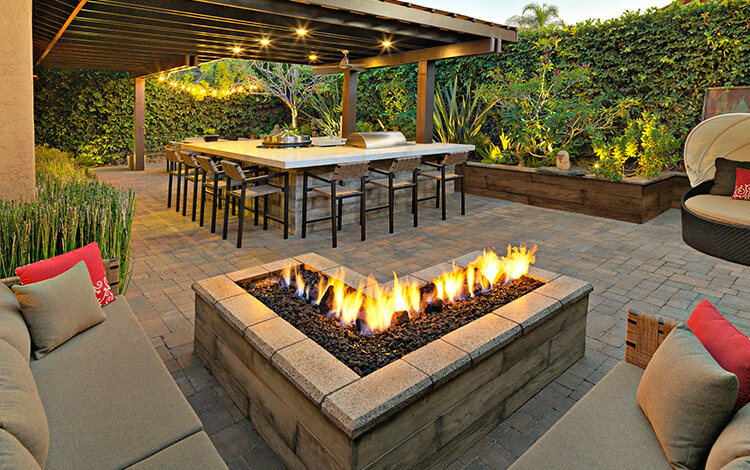 paver backyard with fire pit, pergola, and outdoor kitchen
