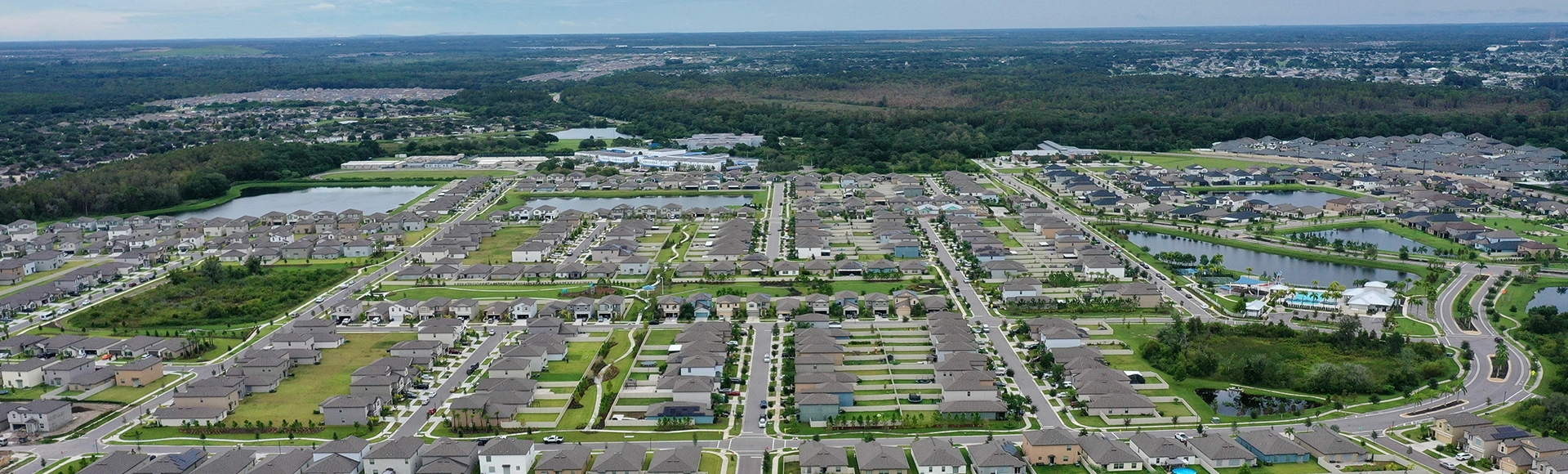 
Aerial view of a suburb in Austin, Texas with trees and a cloudy sky in the background.