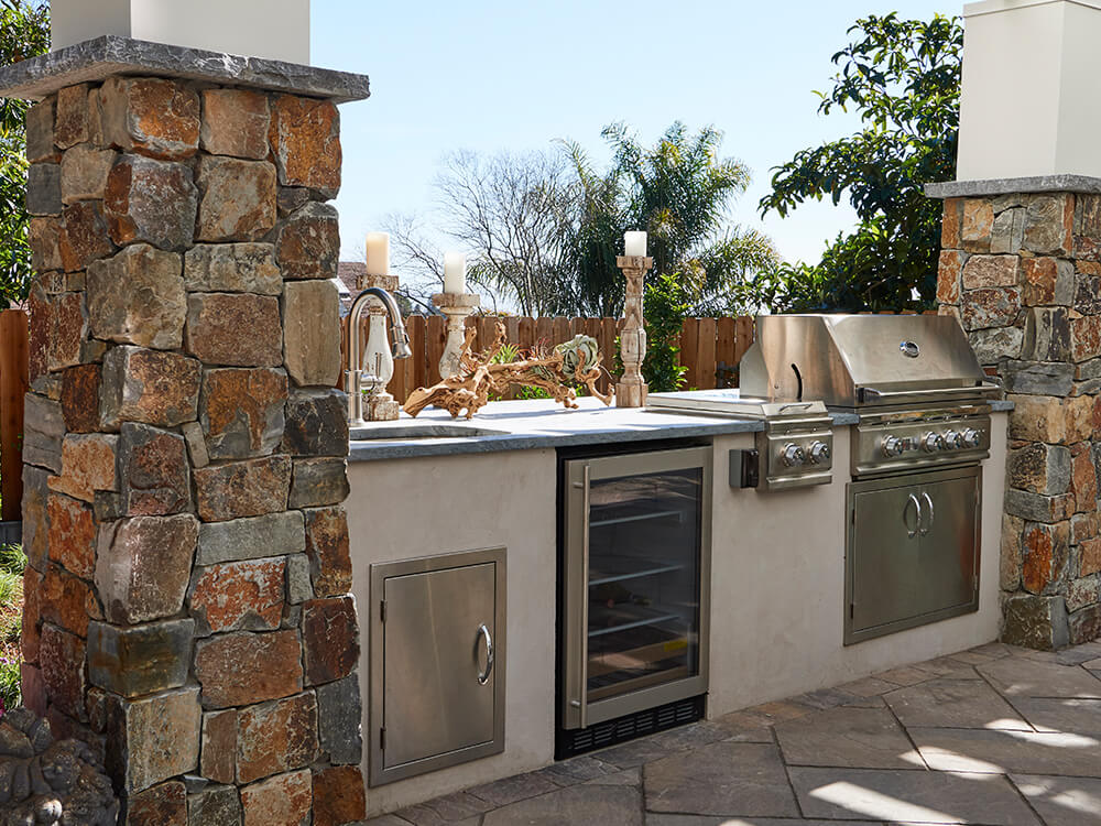 Outdoor kitchen with grilling station, wine fridge and sink. 