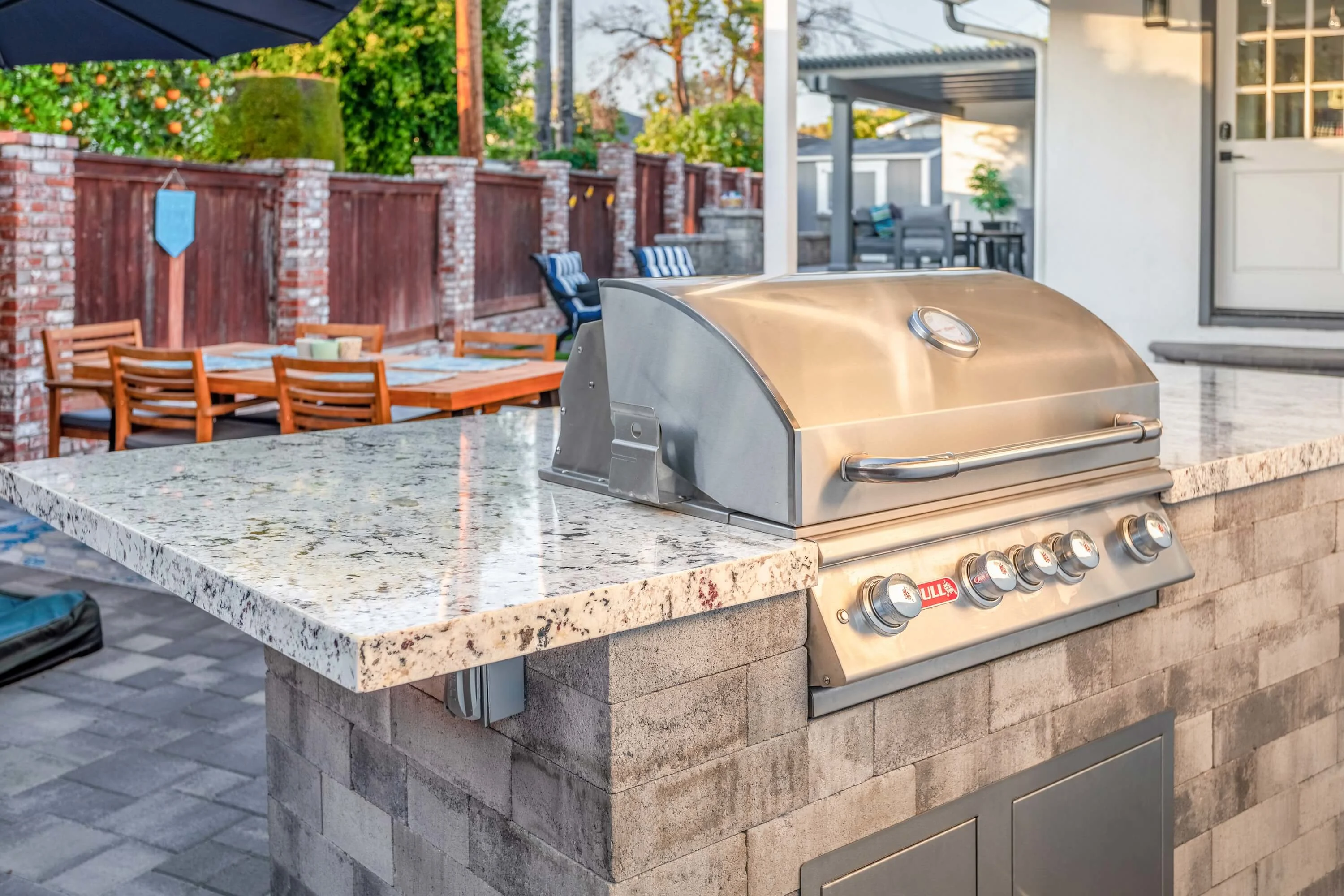Modern grilling station with granite countertops and outdoor dining space 