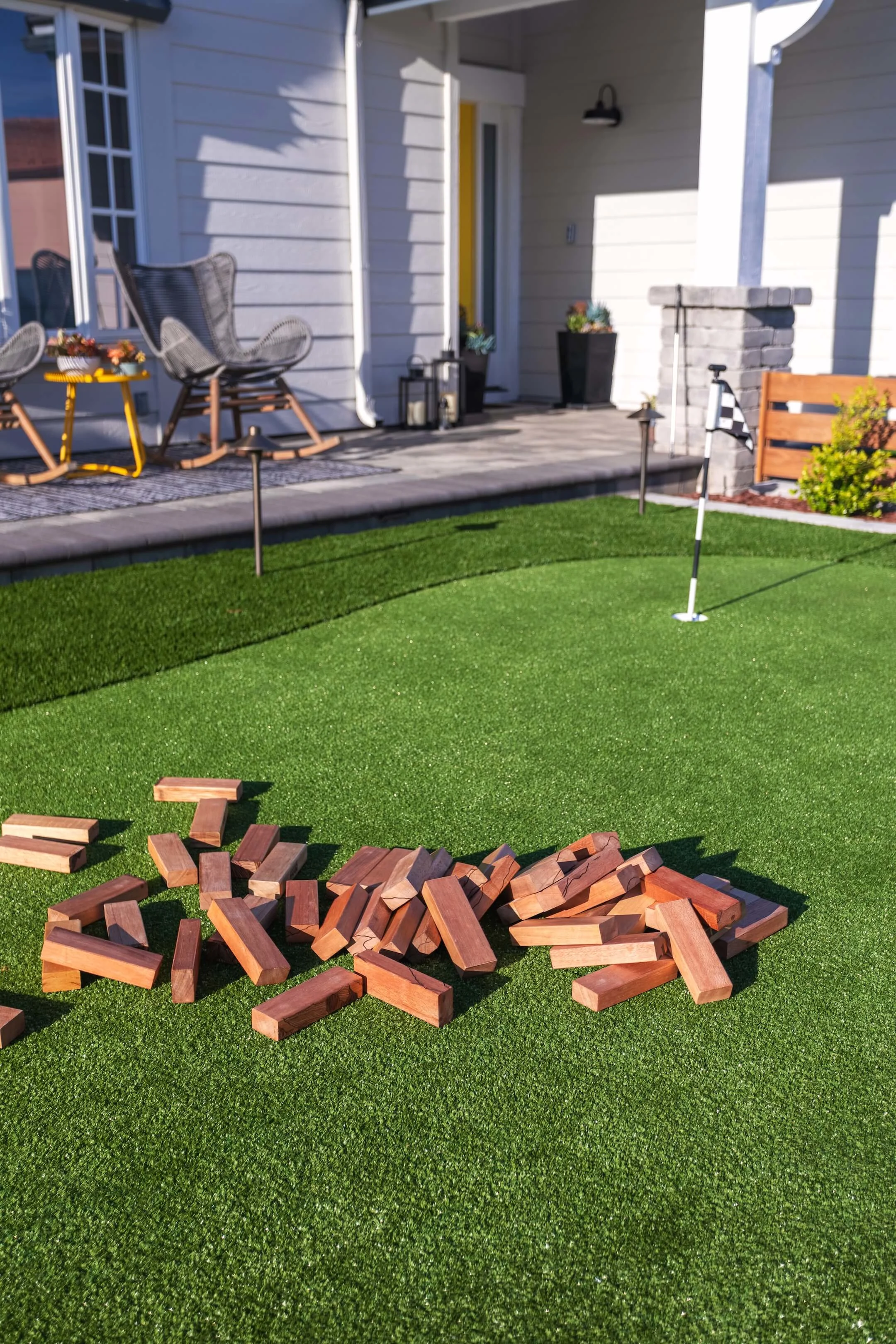 Giant wood blocks on turf putting green front lawn with paver patio entry