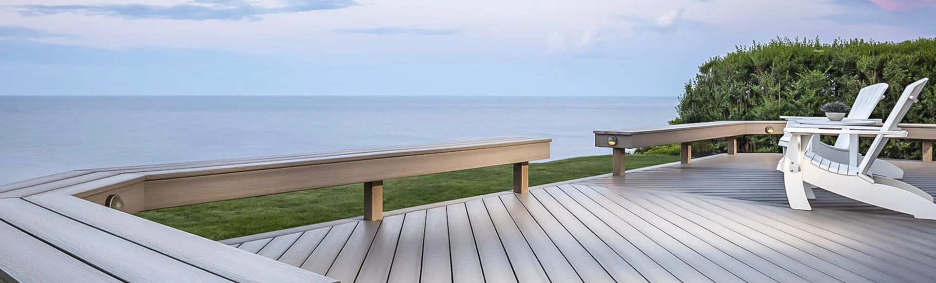 Large backyard composite deck with a view of water.