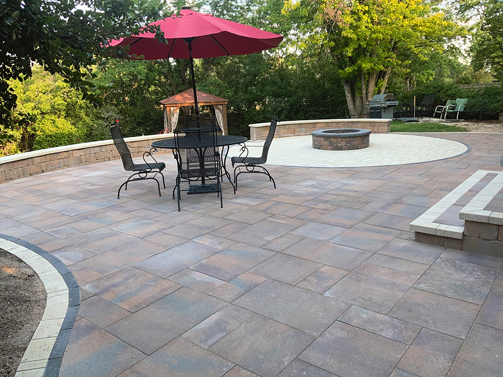 Modern small paver patio with raised planters and bench in Denver, Colorado with a red umbrella 