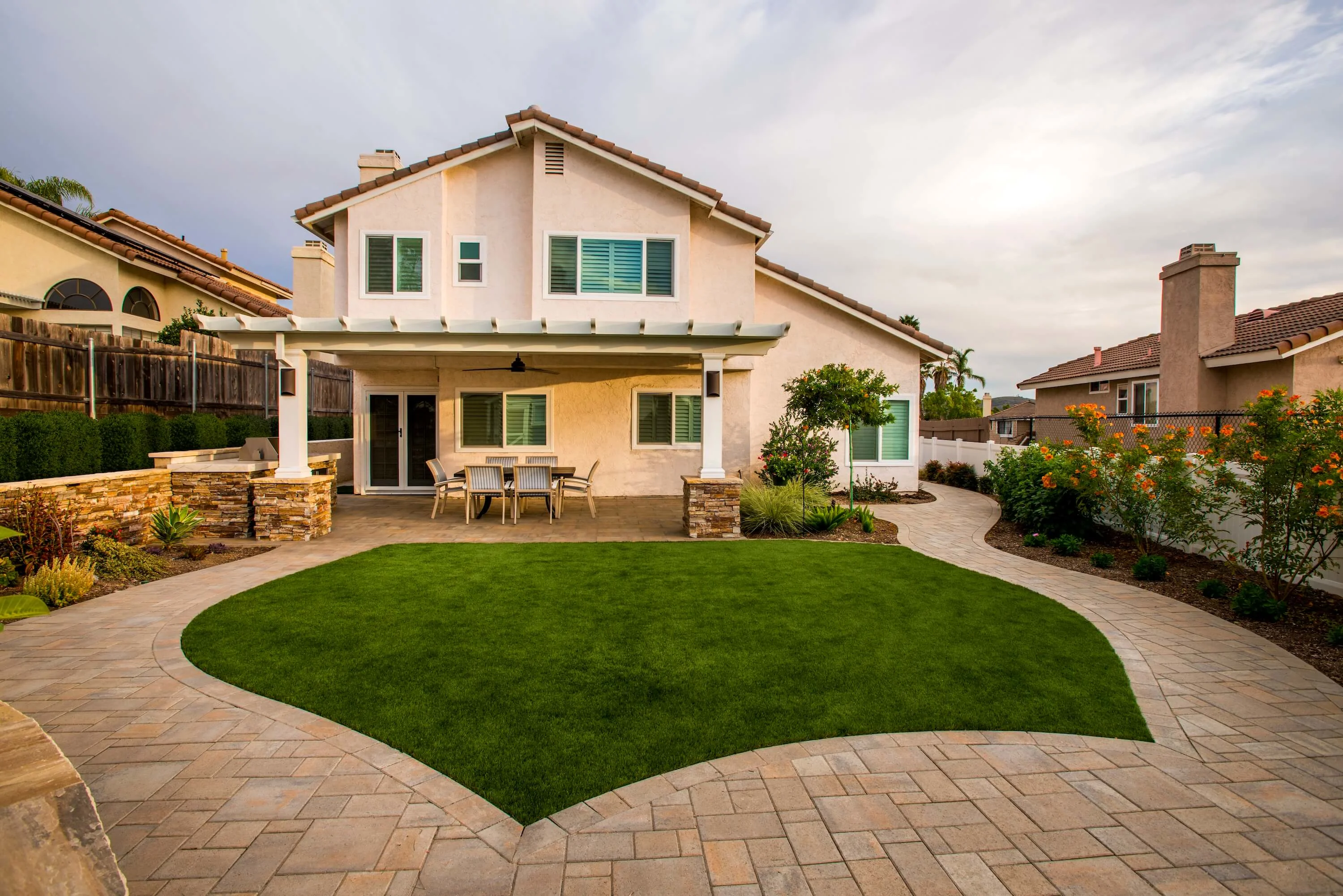 Turf and paving stone backyard with pergola and outdoor dining area