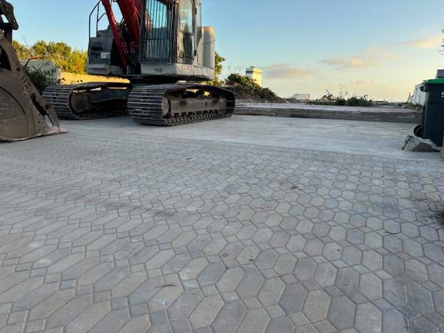 Paving stone driveway with heavy machinery demolished house at sunset