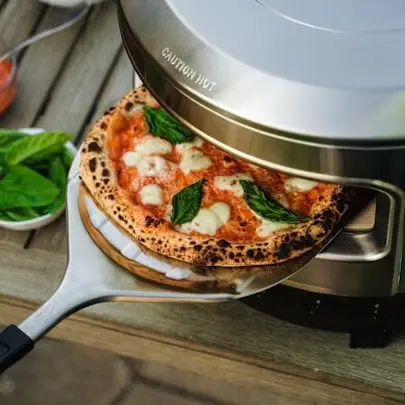 Pizza in Solo Stove Pi Pizza Oven with Stainless Steel Pizza Turner