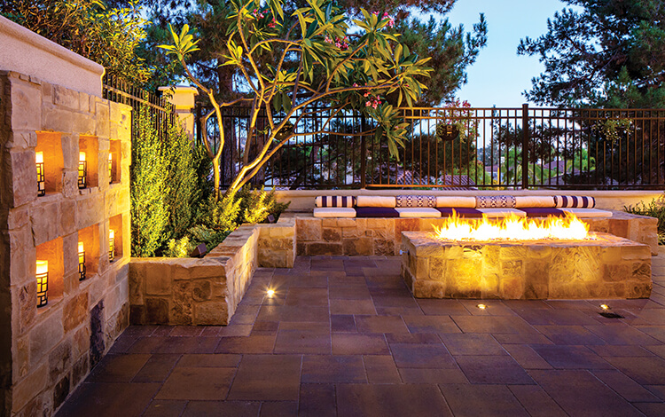 Paving stone patio with built-in stone fire pit and built-in wall with candles and lights. 