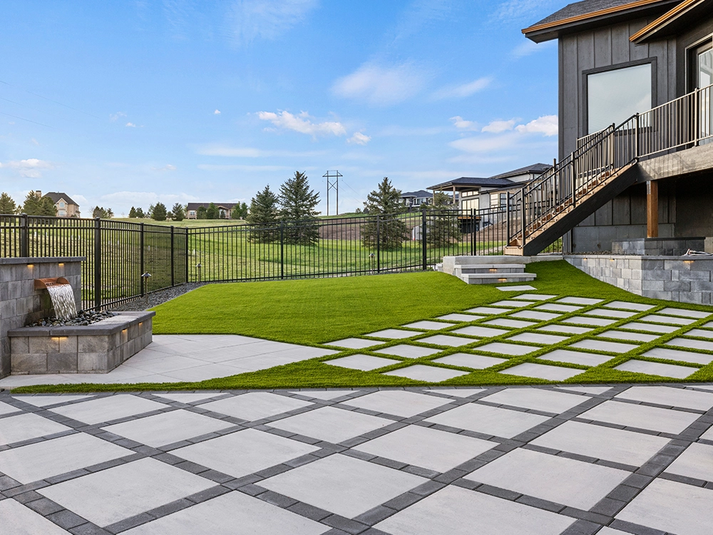 Backyard designed with large pavers, artificial turf and a water feature. 