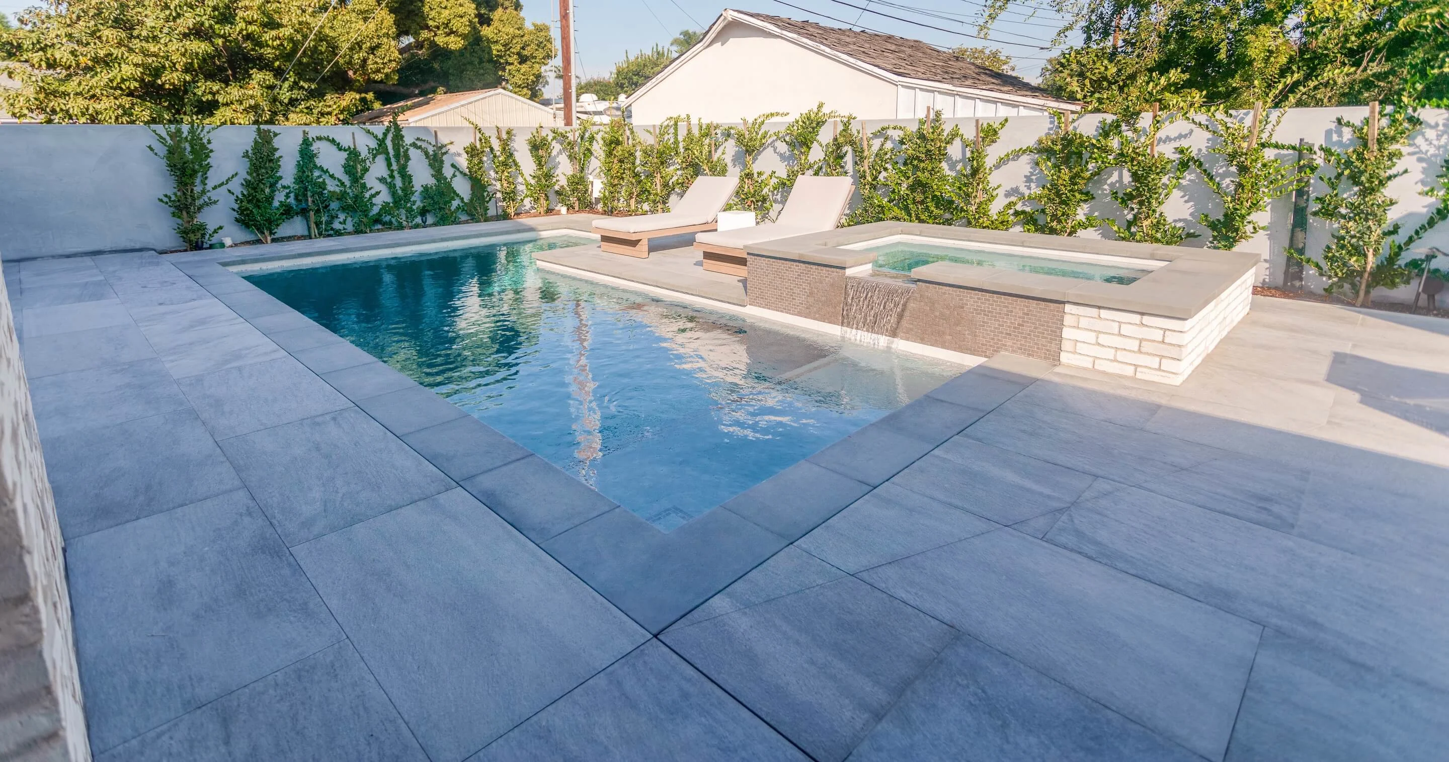 Paver pool deck with large format paving stones and waterfall hot tub