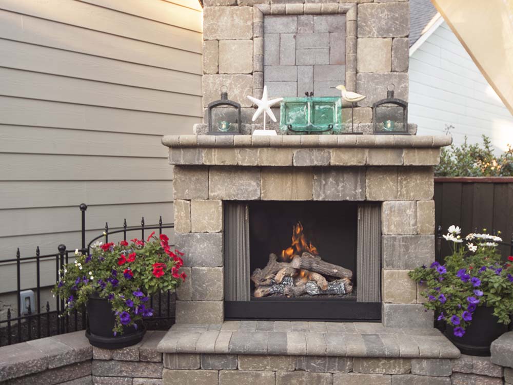 Outdoor fireplace, fire, lit, chimney, mantle, outdoor living, paving stones, flowers, universal region, daytime