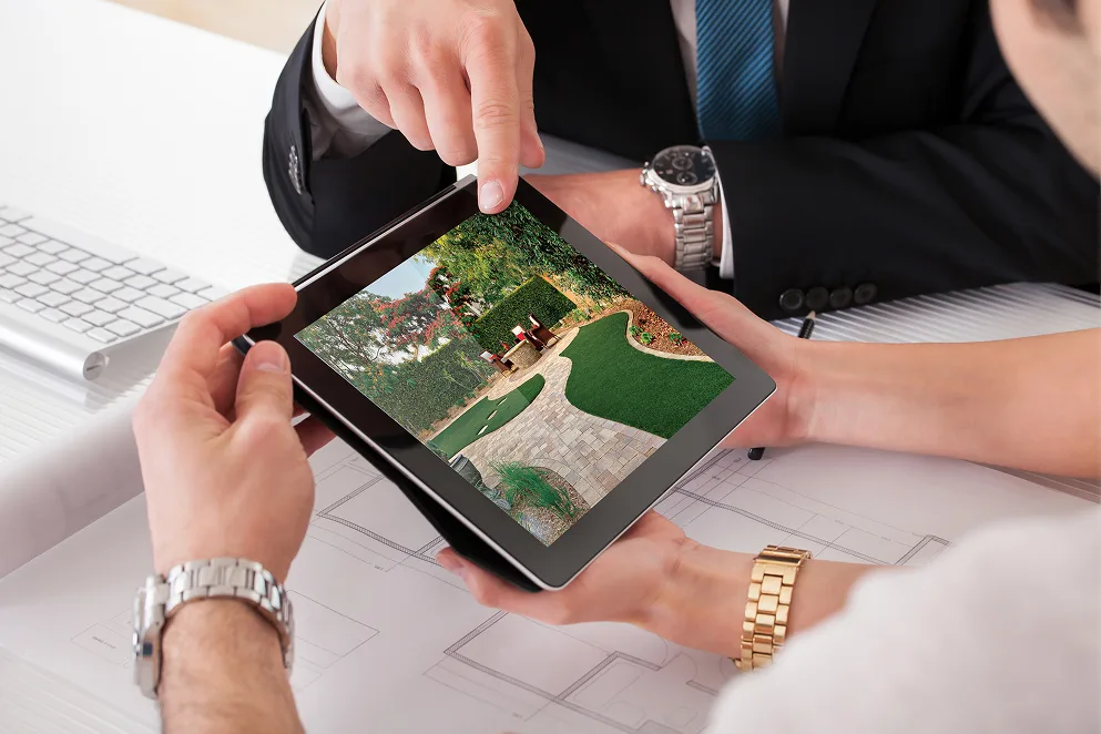 Landscape sales and design professionals reviewing a custom project on a tablet, reflecting a collaborative, client-focused, and tech-savvy work environment.