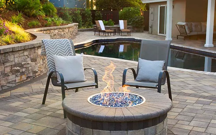Fire pit, gas fire pit, lit, paver pool deck, pool, patio furniture, backyard, paving stones, steps, universal region, daytime