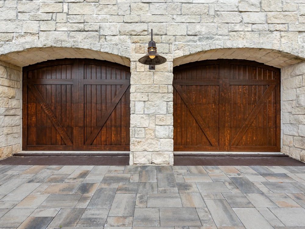 Beautiful wooden garage doors on paving stone driveway in Houston, Texas. 