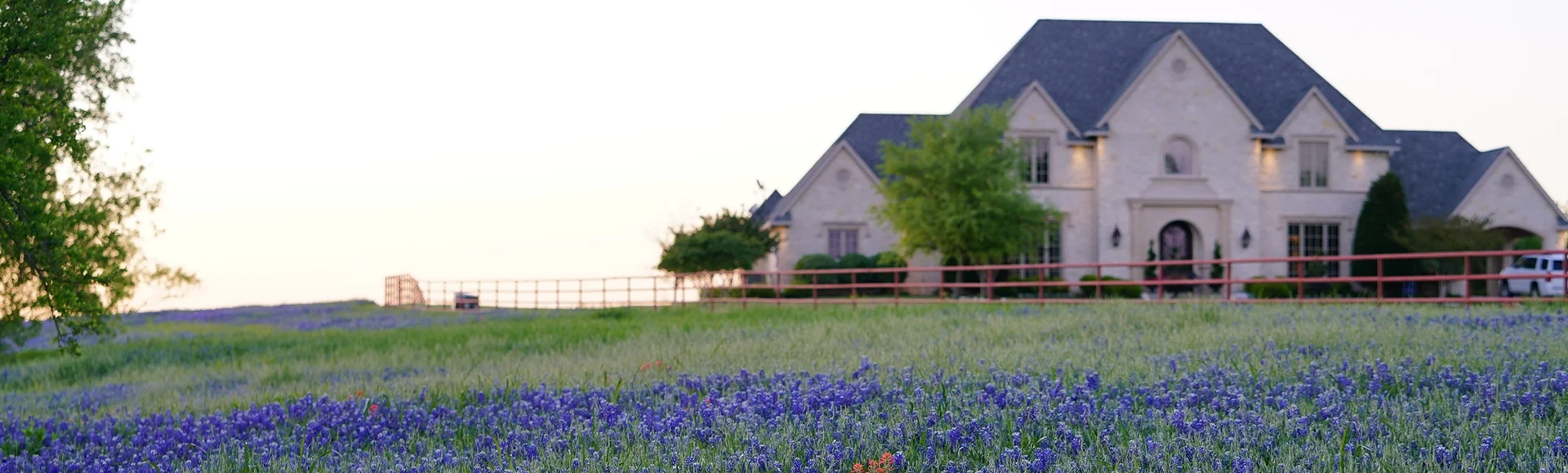 Large countryside home during spring time with Bluebonnet wildflowers blooming