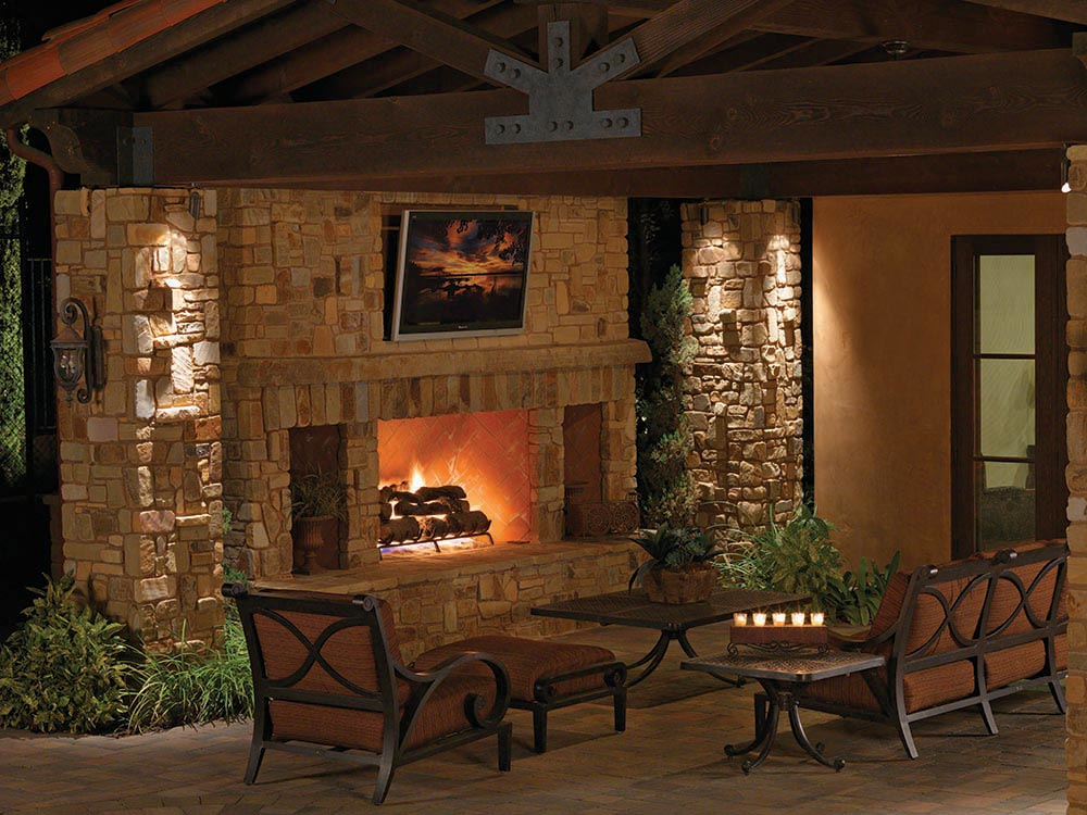 Outdoor fireplace, chimney, mantle, candles, outdoor lighting, covered fireplace, patio furniture, outdoor living room, cozy, paving stones, universal region, night