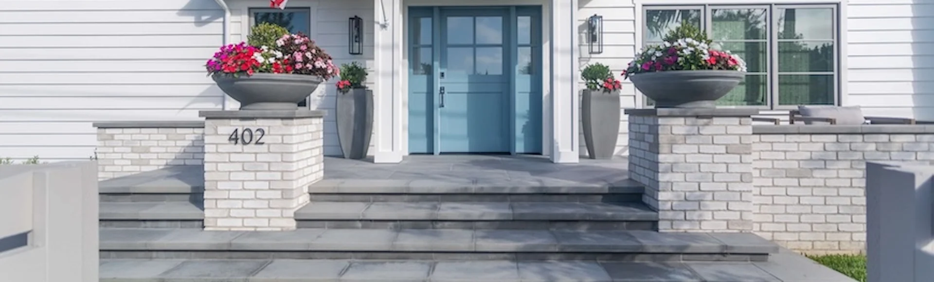 Paver patio front entry and walkway with American flag and flowers