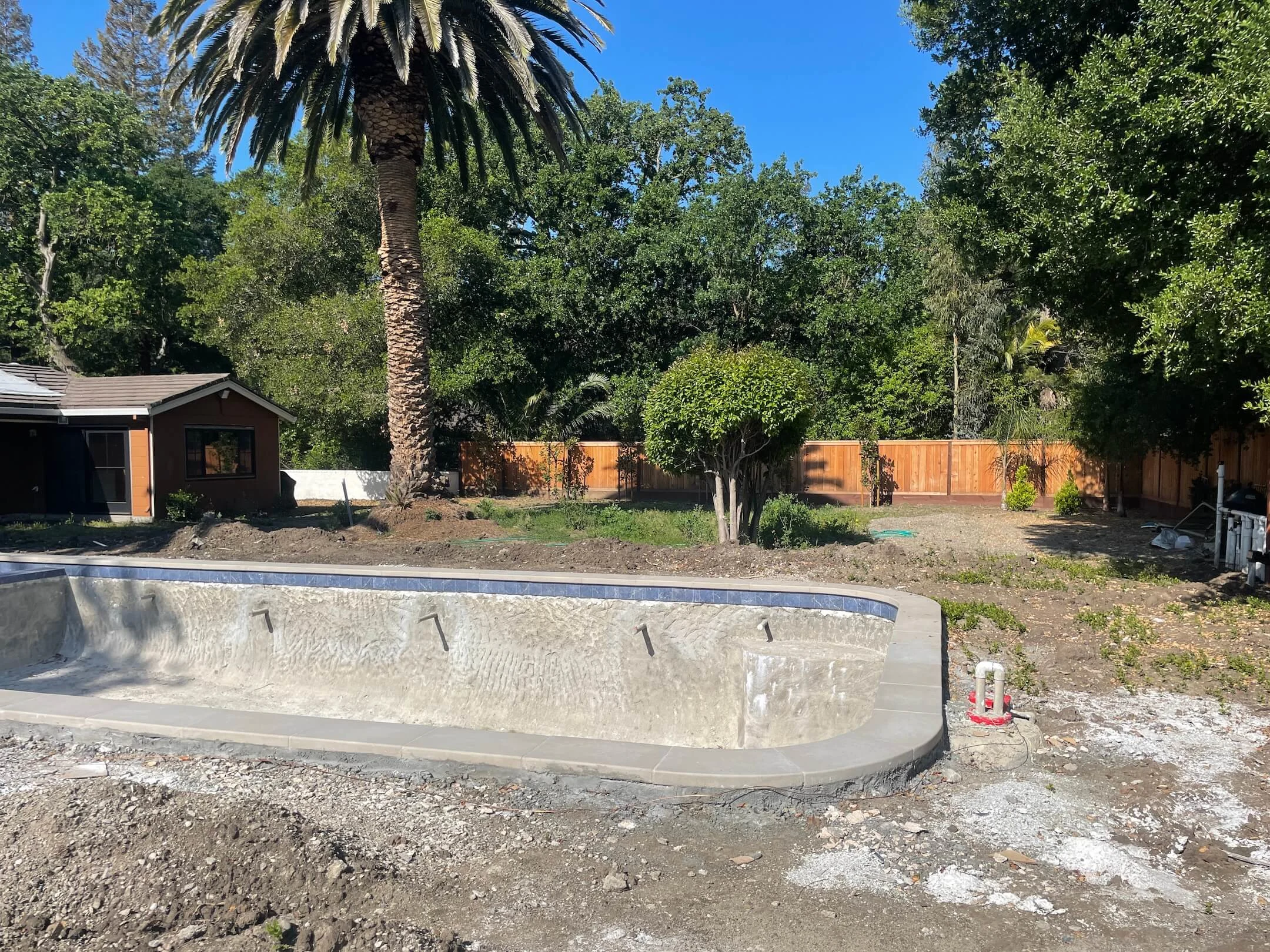 Backyard before with empty pool and dirt yard