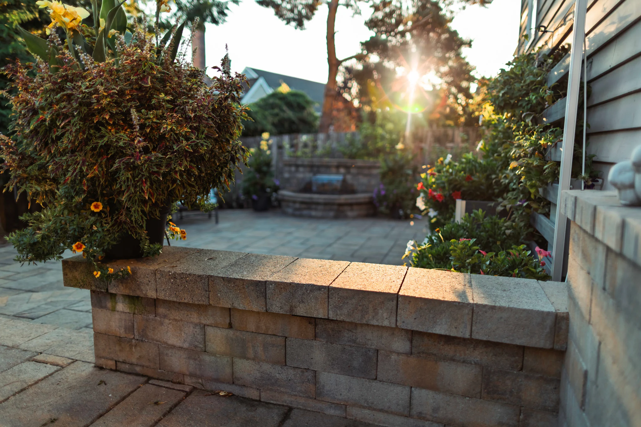 Patio pavers with sitting wall and water feature in background at sunset