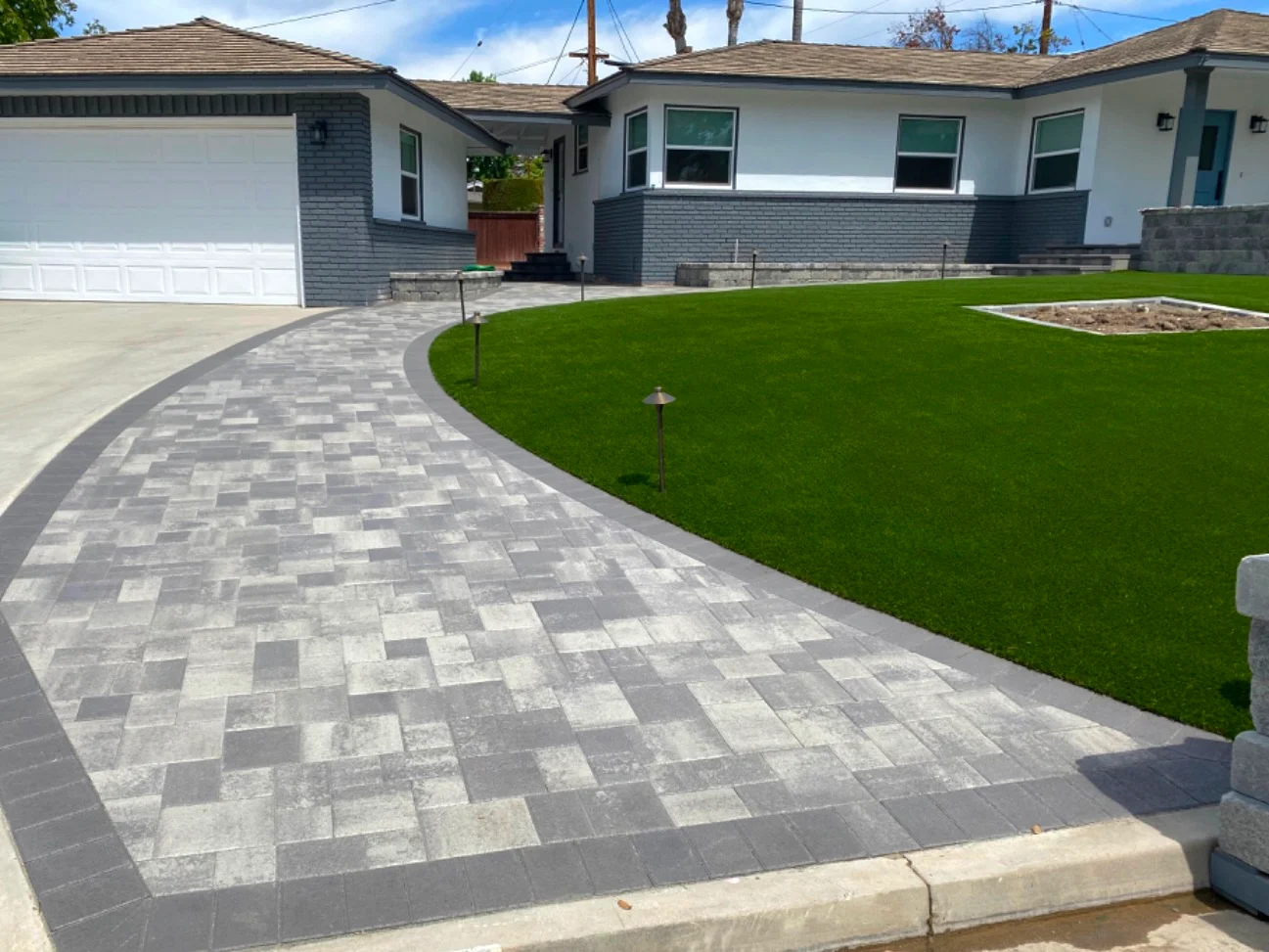Southern California turf front lawn framed by curving paver walkway with landscape lighting and garden beds