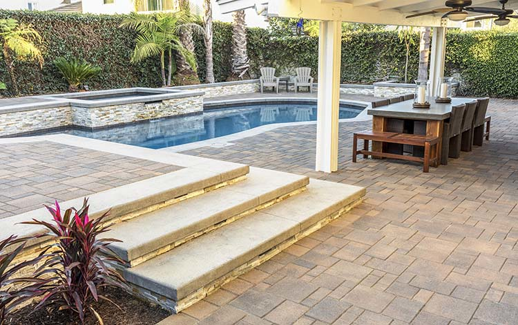 Paver pool deck, pool, water features, pergola, waterfall, patio furniture, backyard, paving stones, steps, California, daytime