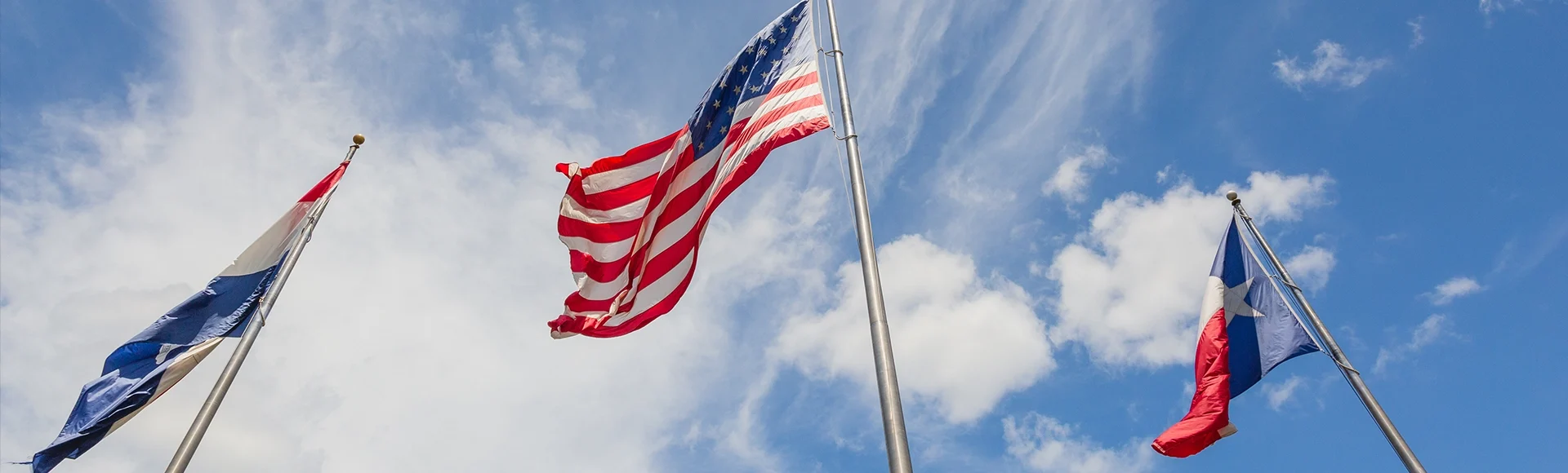 Three flags in the wind: United States, State of Texas, and the town of Friendswood, TX