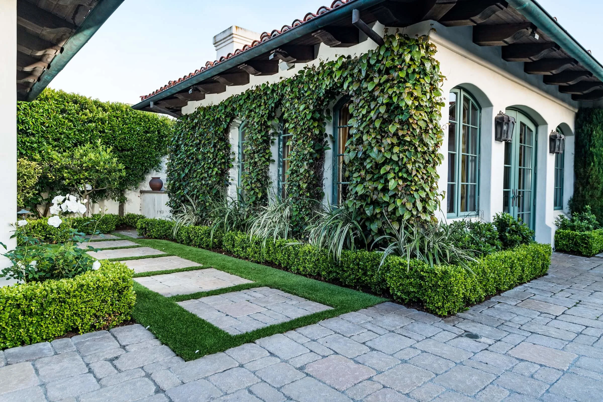 Paving stone courtyard and turf lawn create lush green oasis 