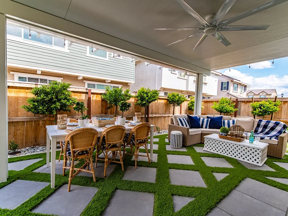 Backyard with paving stone and artificial grass patio under a pergola. 