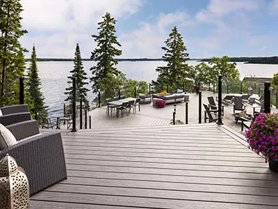 multi-level composite deck with a lake view and evergreen trees