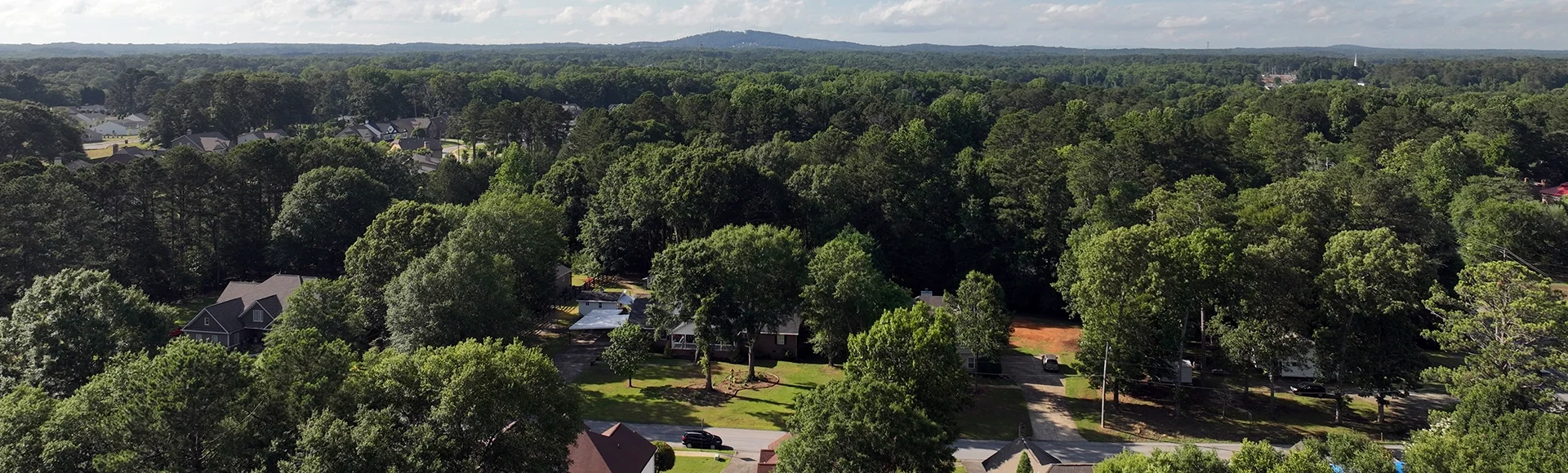 Drone photo of Powder Springs Georgia with white storm clouds. Over tree neighborhoods. Light from sunset. High vantage of Macland Rd. in high quality .