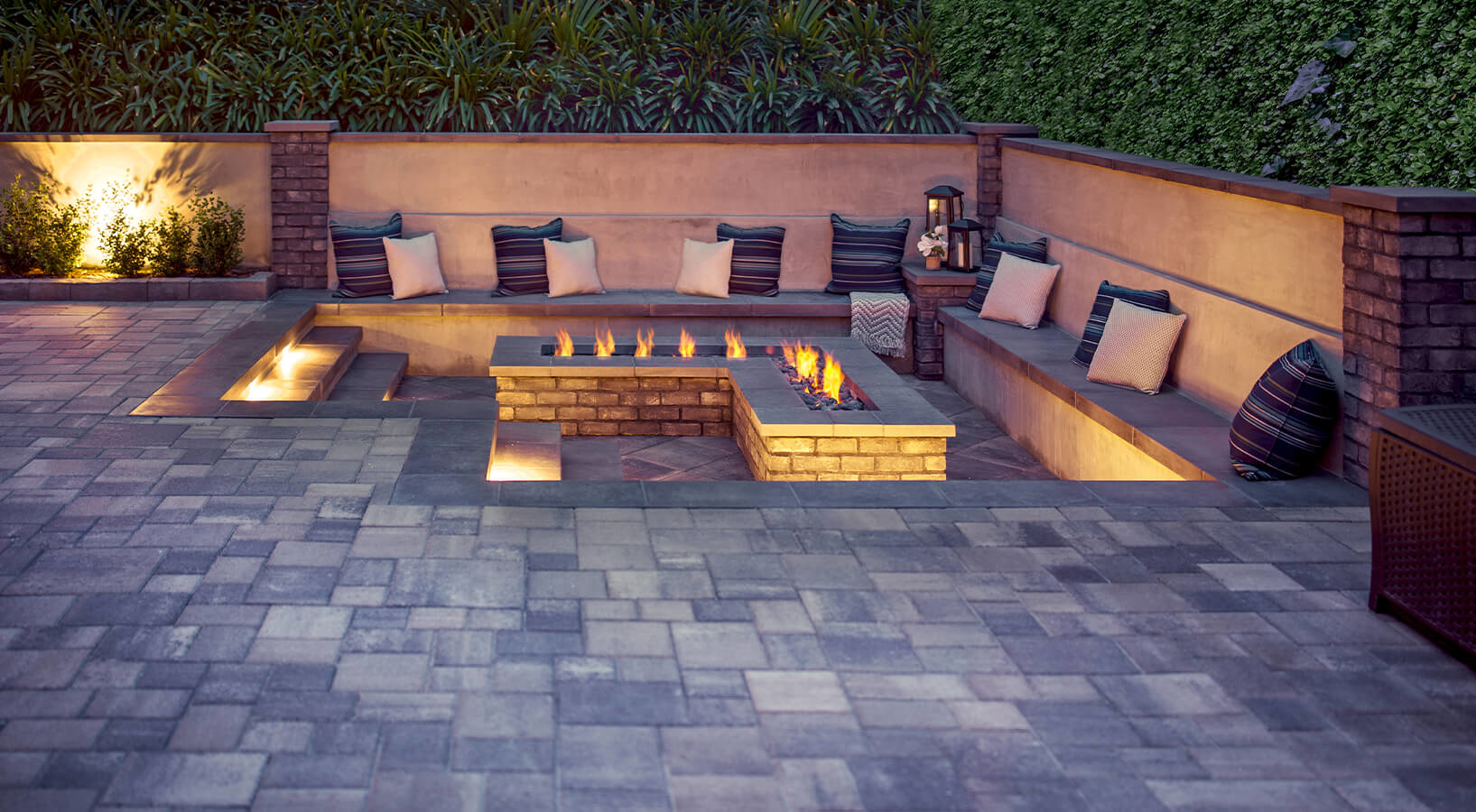 Back yard paver patio with built-in L-shaped fire pit and outdoor lighting