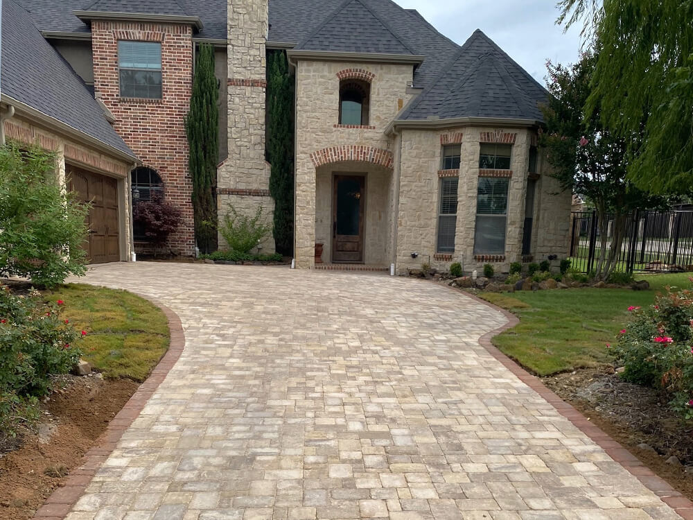 Large white stone home in Texas with paving stone driveway