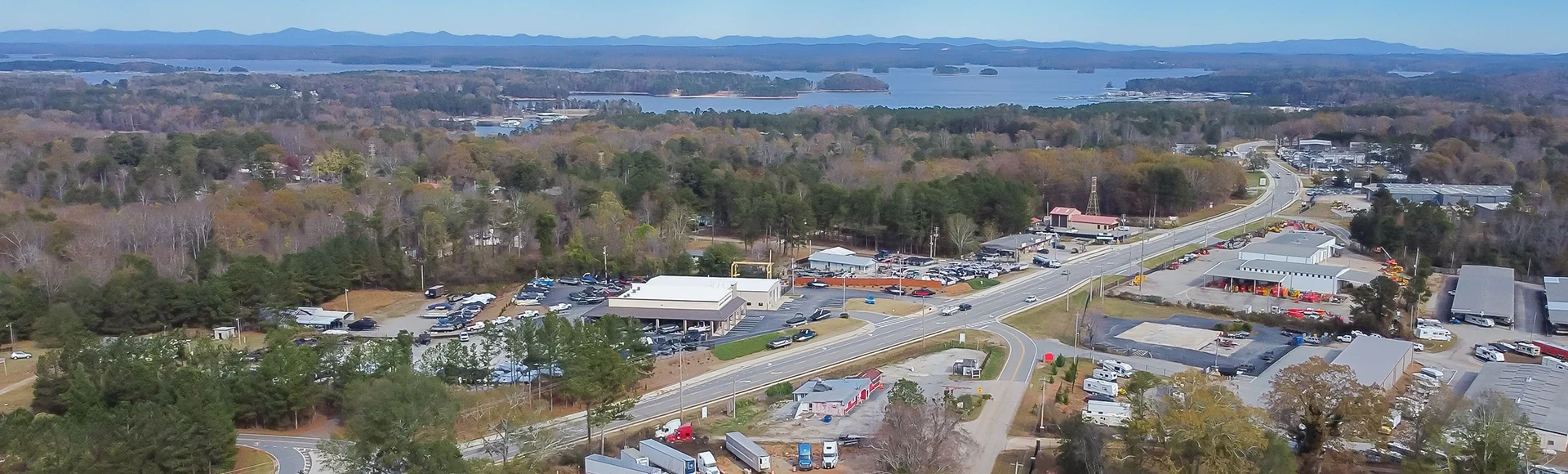 Panorama aerial view Lanier Island Parkway with farm ranch style residential houses, commercial buildings and Lake Lanier in background in Buford, America 