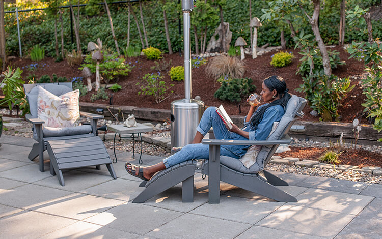 Black woman enjoying a book and a beverage on a paving stone patio in Seattle