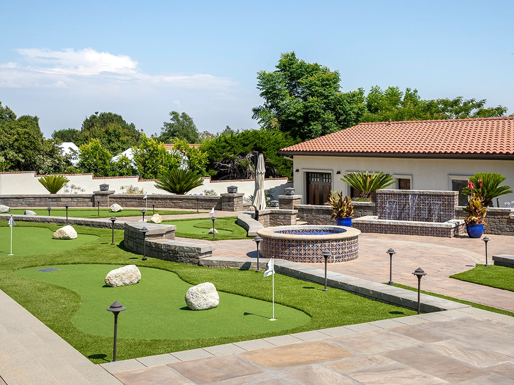 Personal putting green by a fire pit and paver patio. 