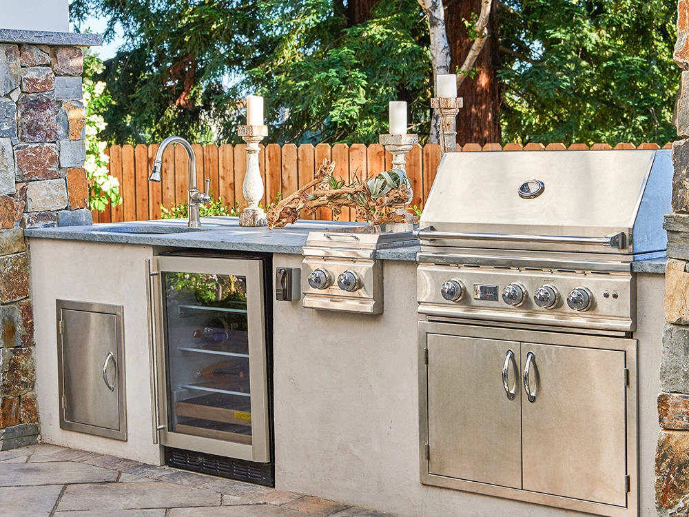 Outdoor kitchen with grill, wine cooler, sink and more. 