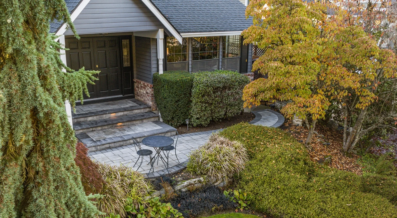 Pacific Northwest front yard with paver driveway and lighting. 