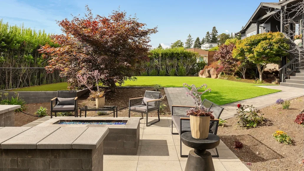 PNW backyard transformation with fire pit, sitting wall, and paver walkway