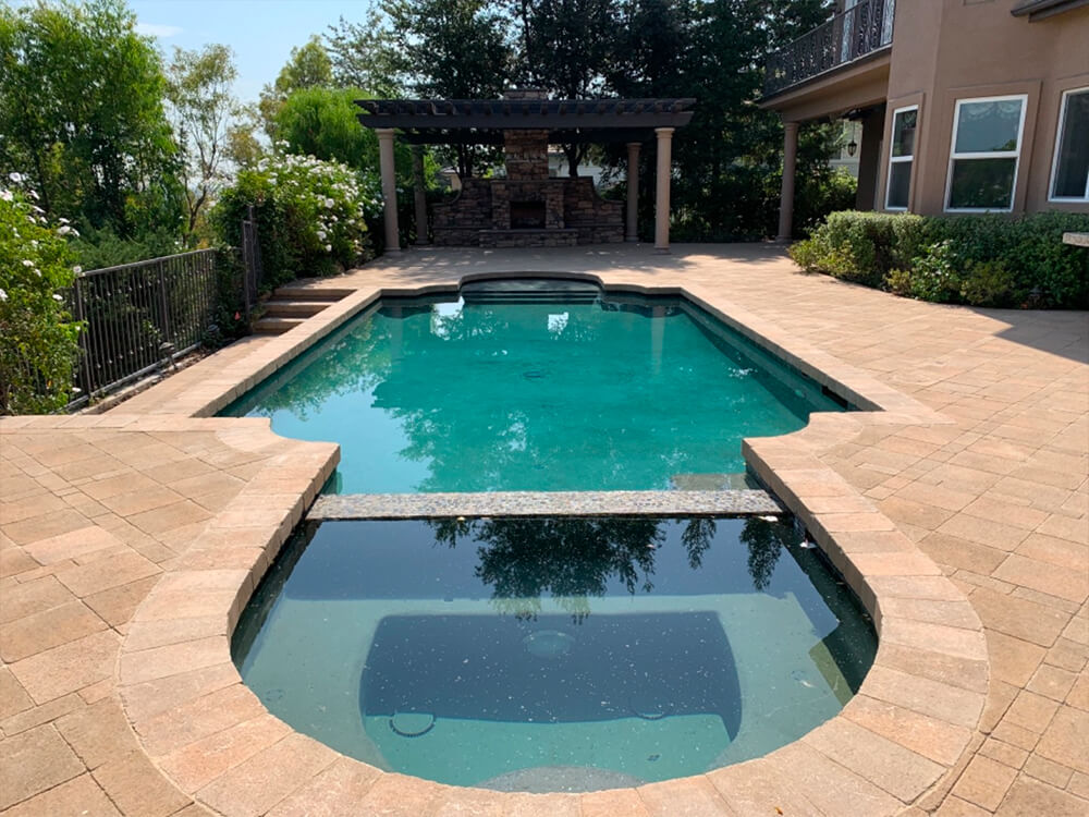 Paving stone pool deck with jacuzzi and pergola