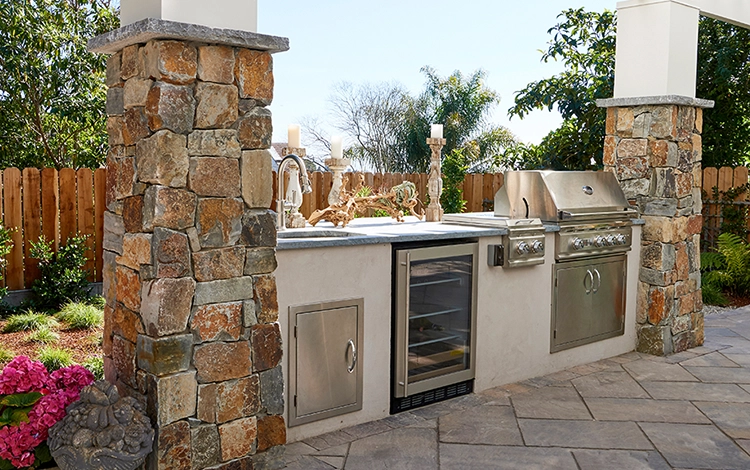 Stone paver outdoor kitchen with grill, fridge, storage and sink