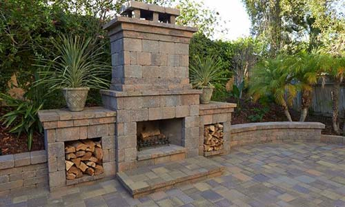 Outdoor fireplace, paver patio, retaining wall, wood, wood-burning fireplace, outdoor living, backyard, paving stones, California, daytime