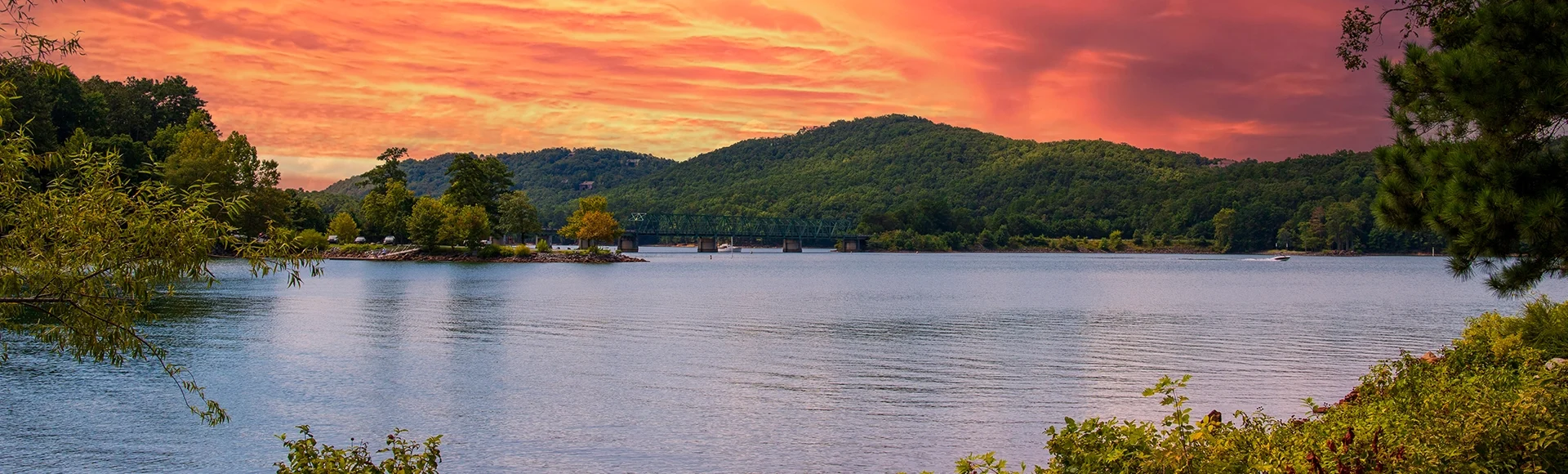 A gorgeous summer landscape at Lake Allatoona with green water surrounded by lush green trees, grass and plants with powerful clouds at sunset at Red Top Mountain State Park in Acworth Georgia 