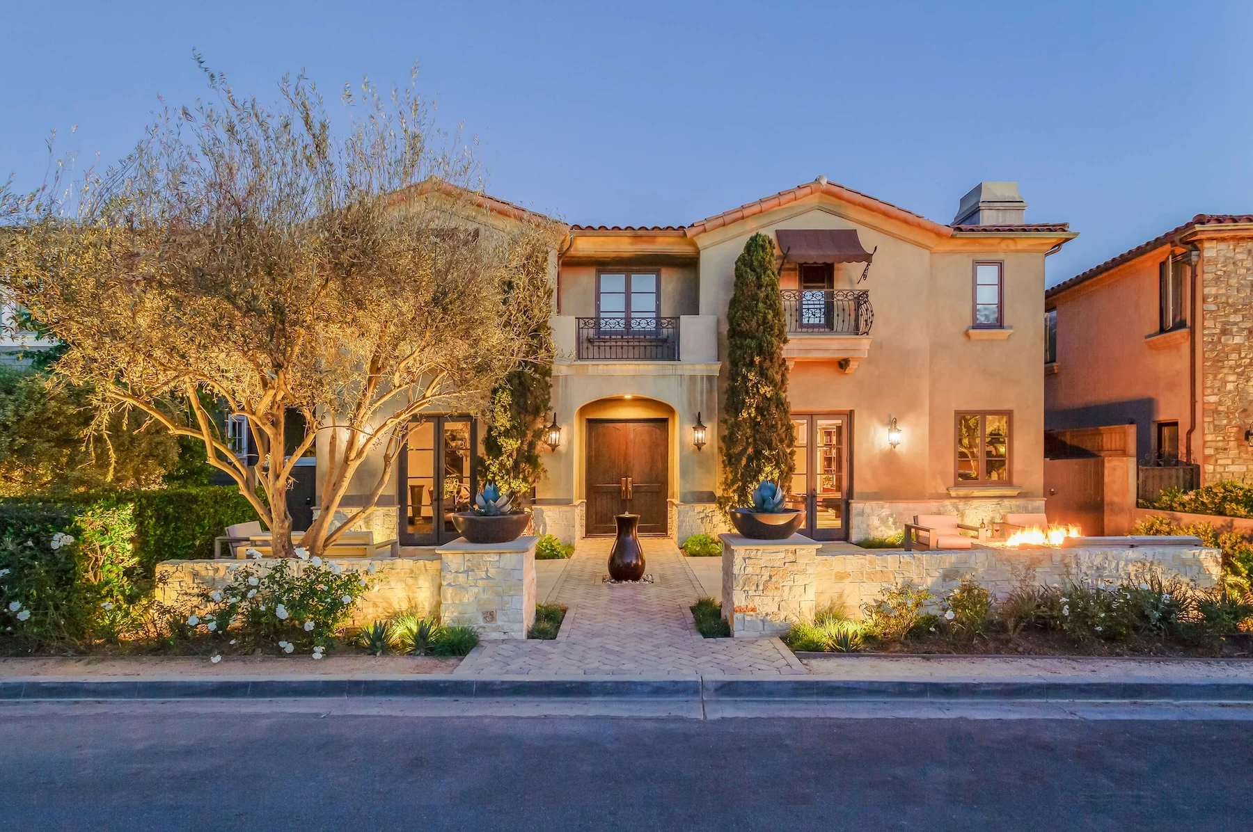 Beautiful front yard remodel with paver courtyard, water feature, sitting walls, fire pit, and landscape lighting 