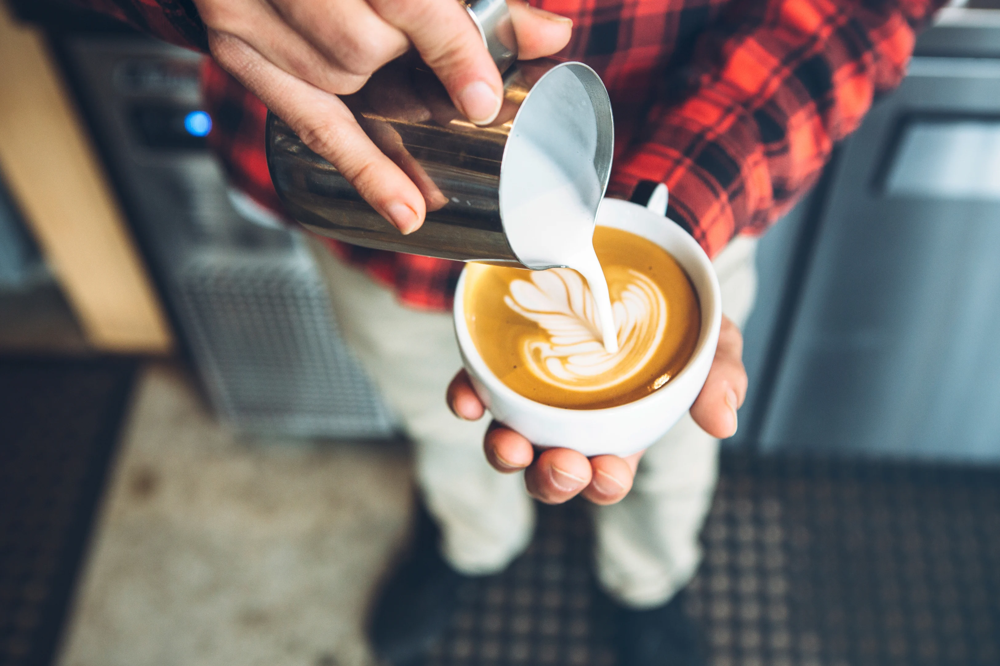 Geschäumte Milch wird zu Kaffee gegossen