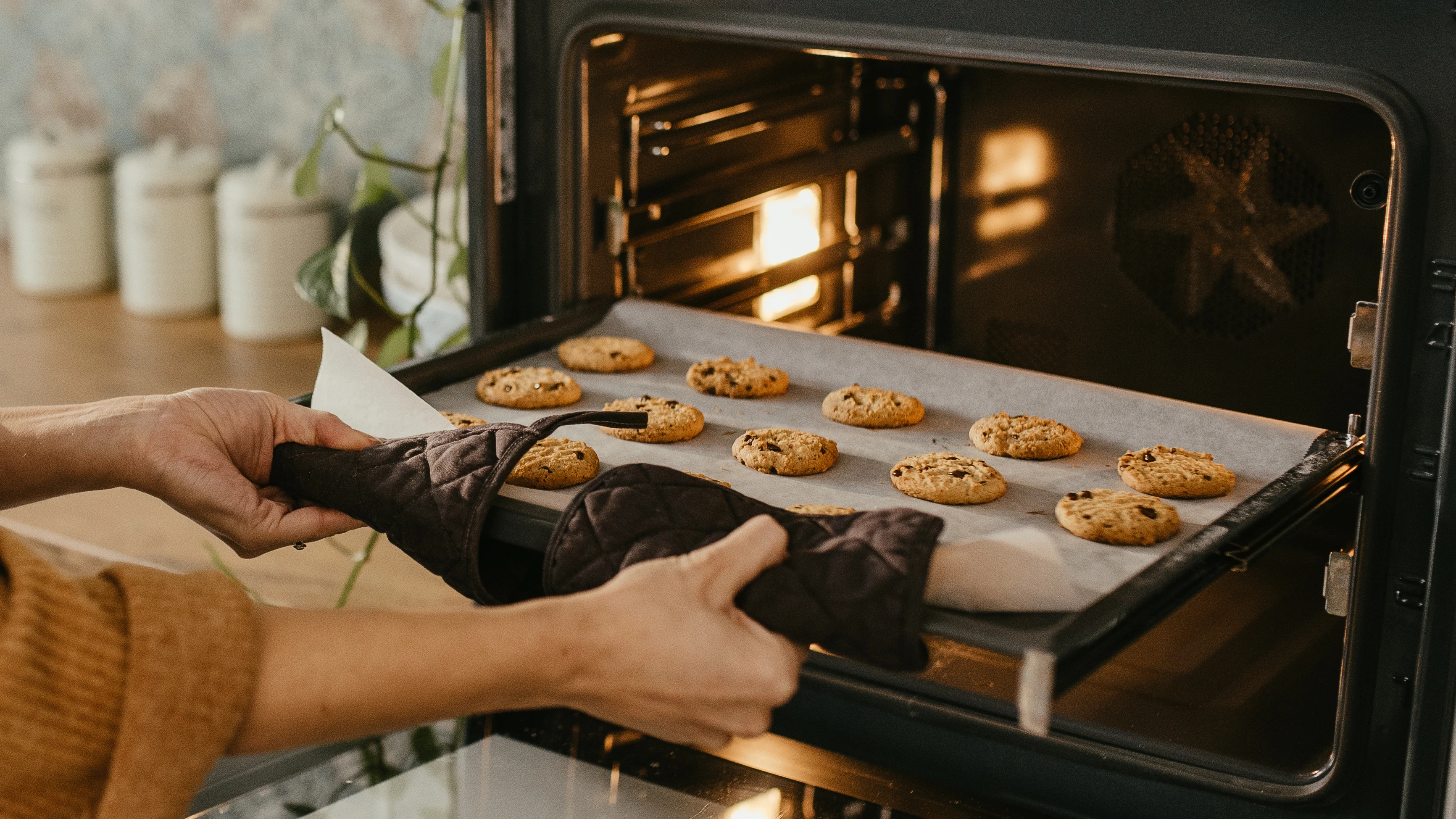 Femme sortant une plaque pleine du biscuits du four, comment économiser de l'énergie