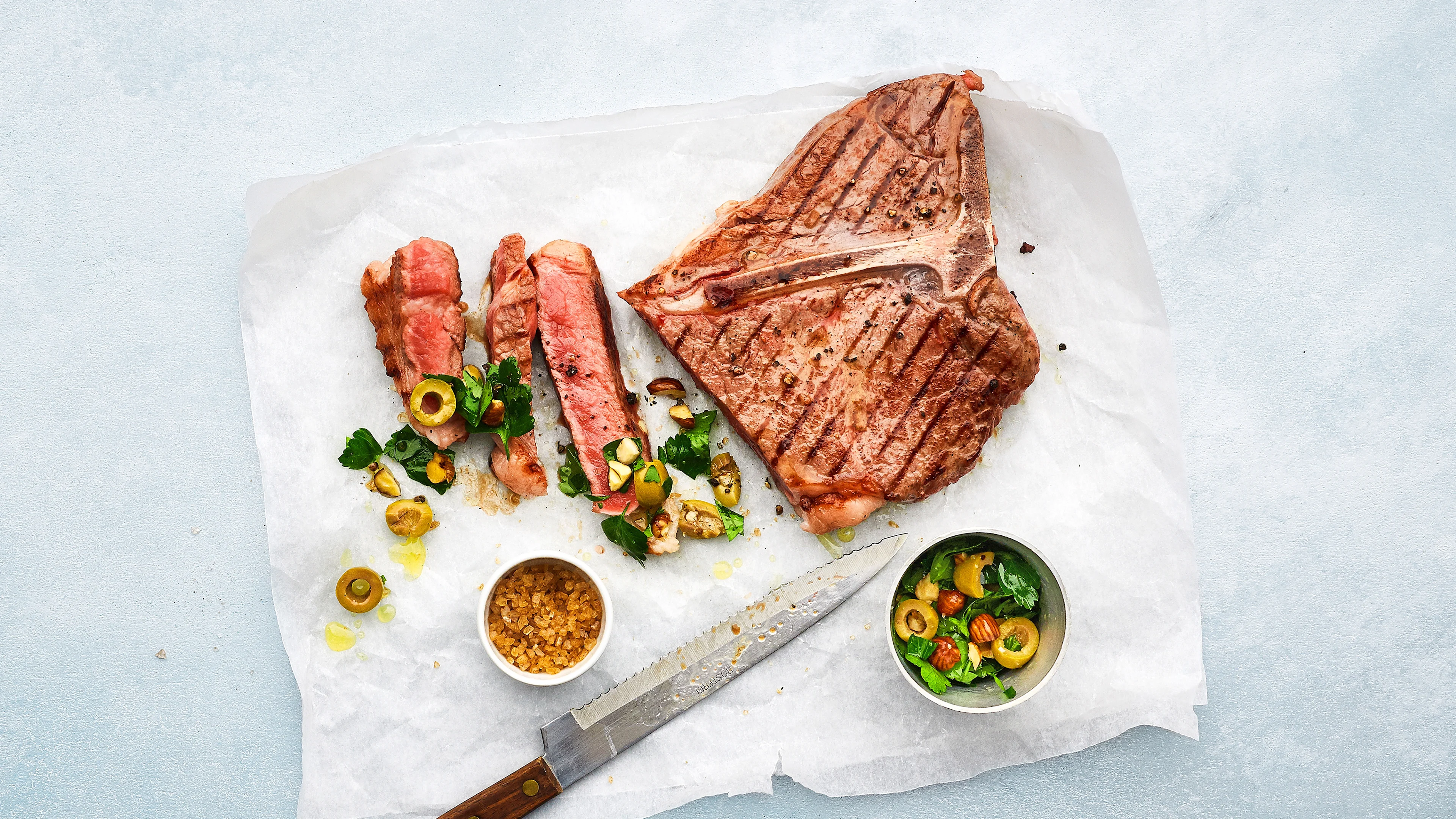 T-bone-steak con topping alle nocciole e olive